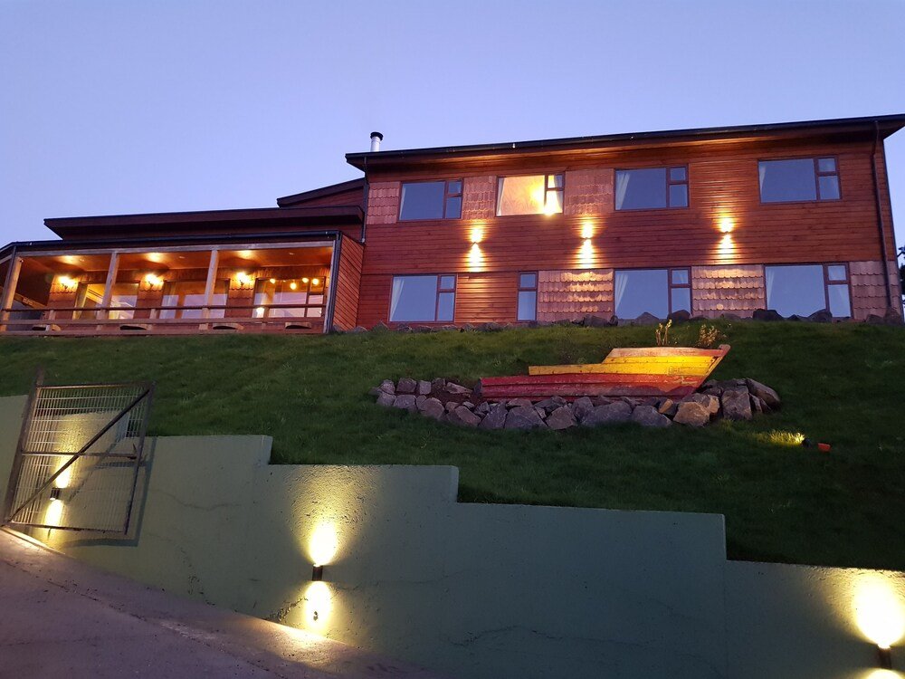 Casa de madera de dos pisos con techo inclinado y pequeño jardín florido