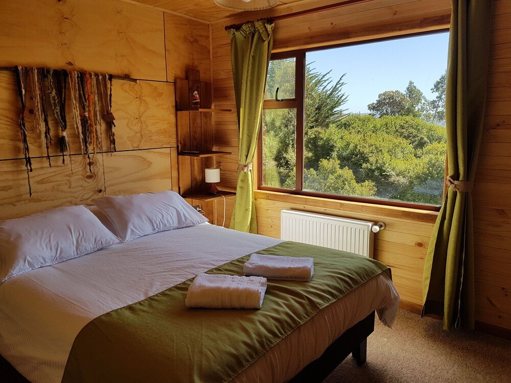 Habitación de madera con cama, ventana y radiador