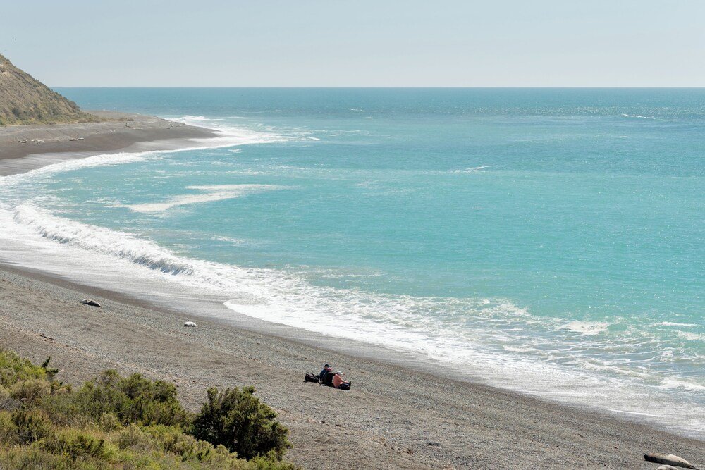 Playa con una duna y una persona caminando cerca