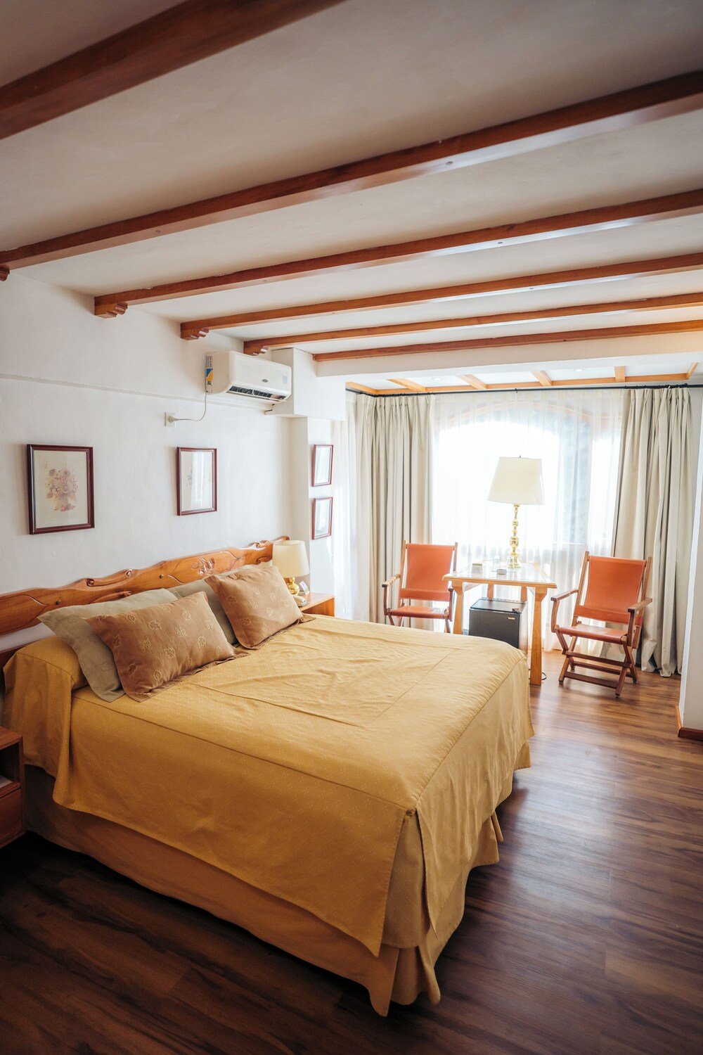 Habitación con cama grande, vigas de madera y una mesa pequeña
