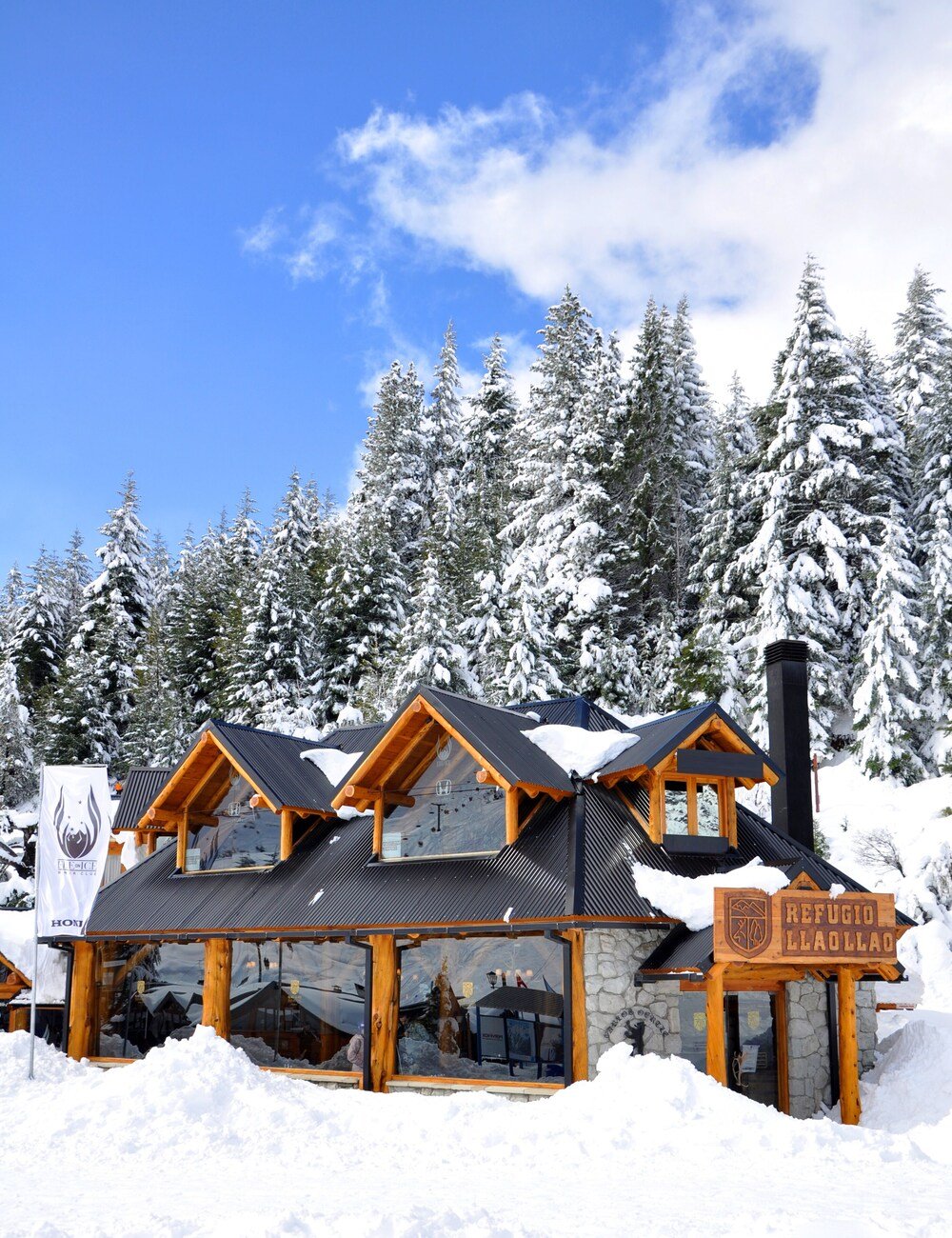 Snow-covered lodge with a stone facade and wooden beams