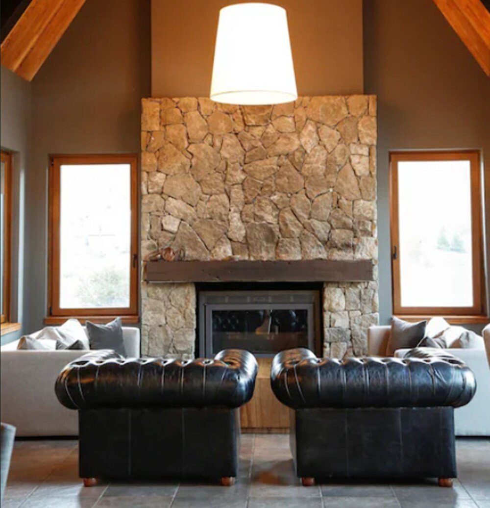 Sala de estar con chimenea de piedra y sillones de cuero