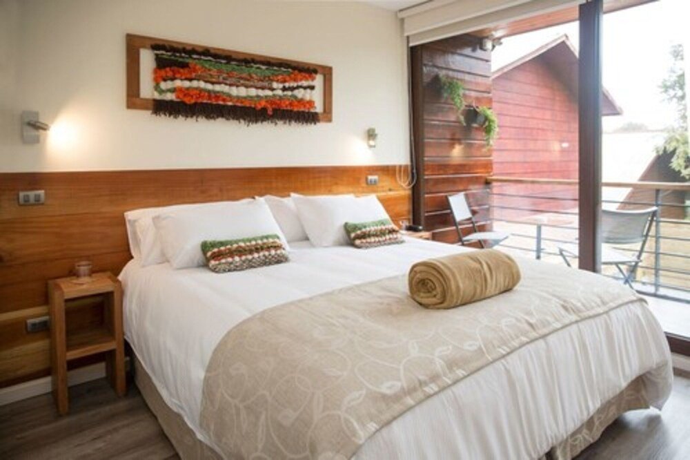 Bedroom with wooden headboard, white linens and decorative pillows