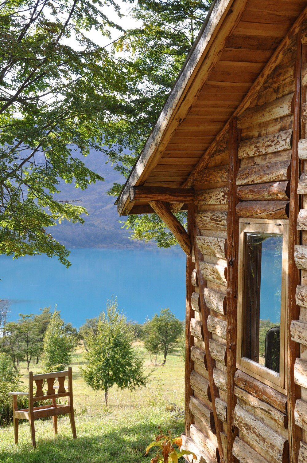 Rústica cabaña de troncos con galería de madera frente al lago