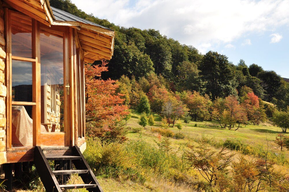 Cabaña de madera con grandes ventanales y terraza de madera