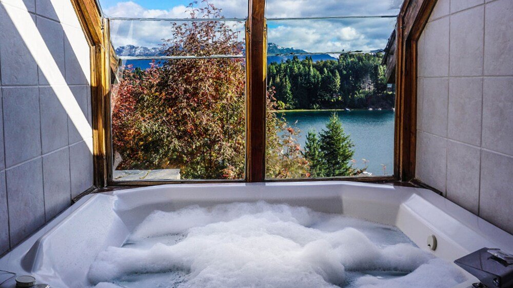 Baño con una gran bañera con espuma y ventana con vista