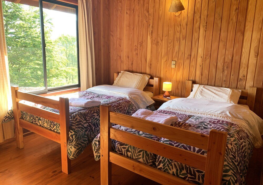 Wooden room with two beds, patterned bedding and a lamp