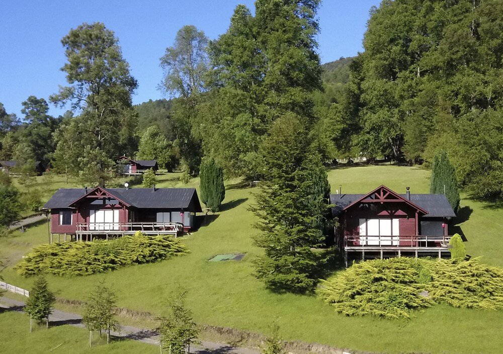 Cluster of cabins with grassy hill and dense trees behind