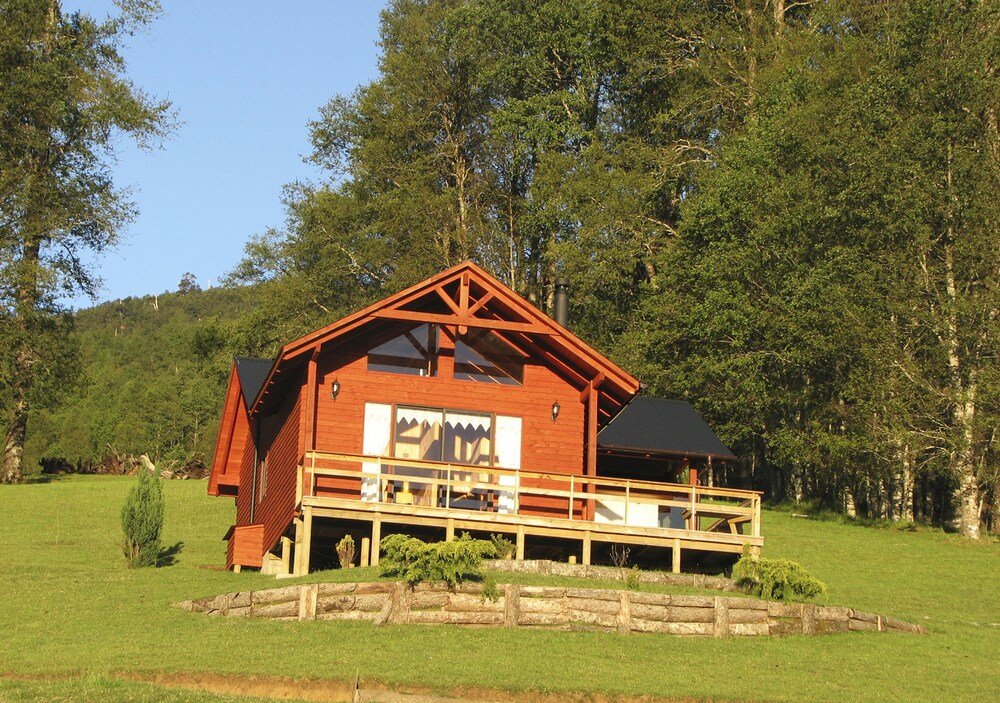 Wooden cabin with balcony, wooden fence and lush greenery
