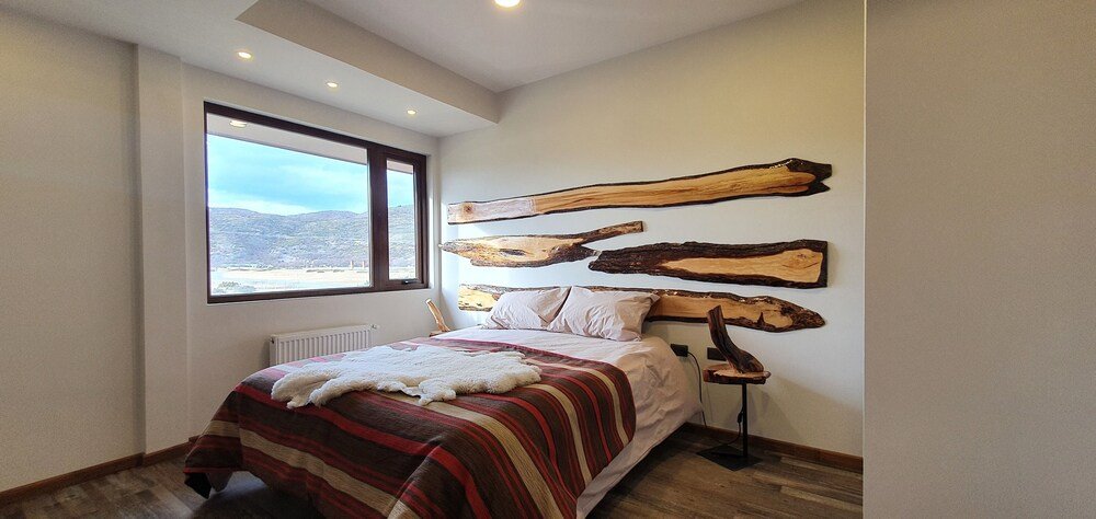 Dormitorio con una gran ventana en Morrena Lodge