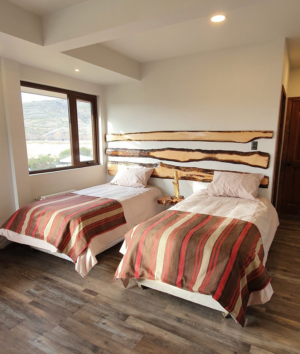 Dormitorio con dos camas y paredes de madera en Morrena Lodge