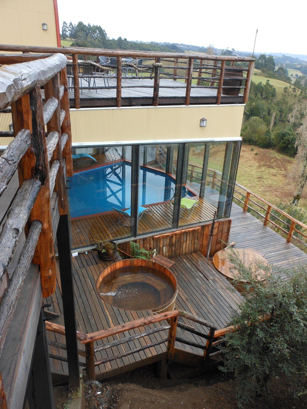 Deck de madera con tina caliente y piscina cerrada con vidrio