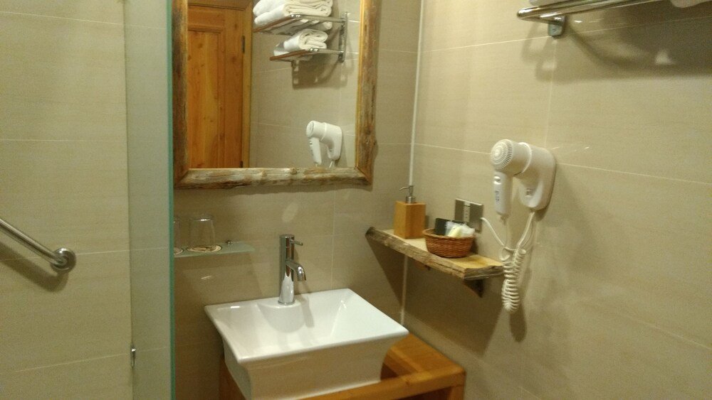 Baño con lavabo, espejo, secador de pelo y toallero
