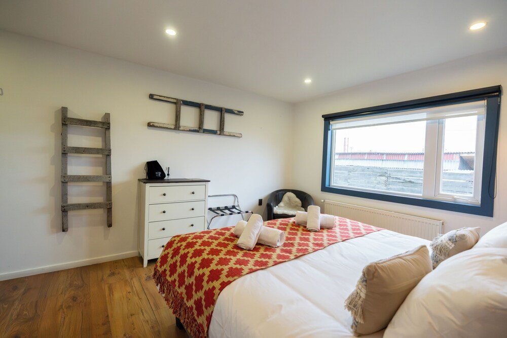 Dormitorio con cama, cómoda y una escalera de madera