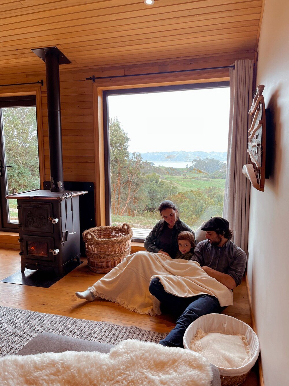 Sala acogedora con estufa a leña, gran ventana y zona de asientos