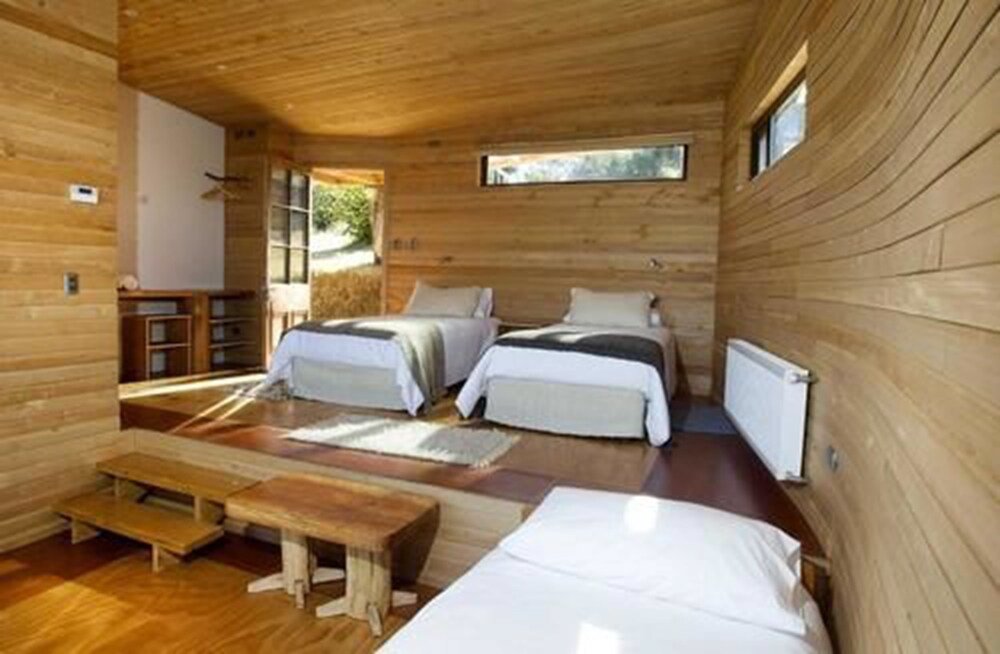 Cabaña de madera con dos camas, un banco y una mesa pequeña