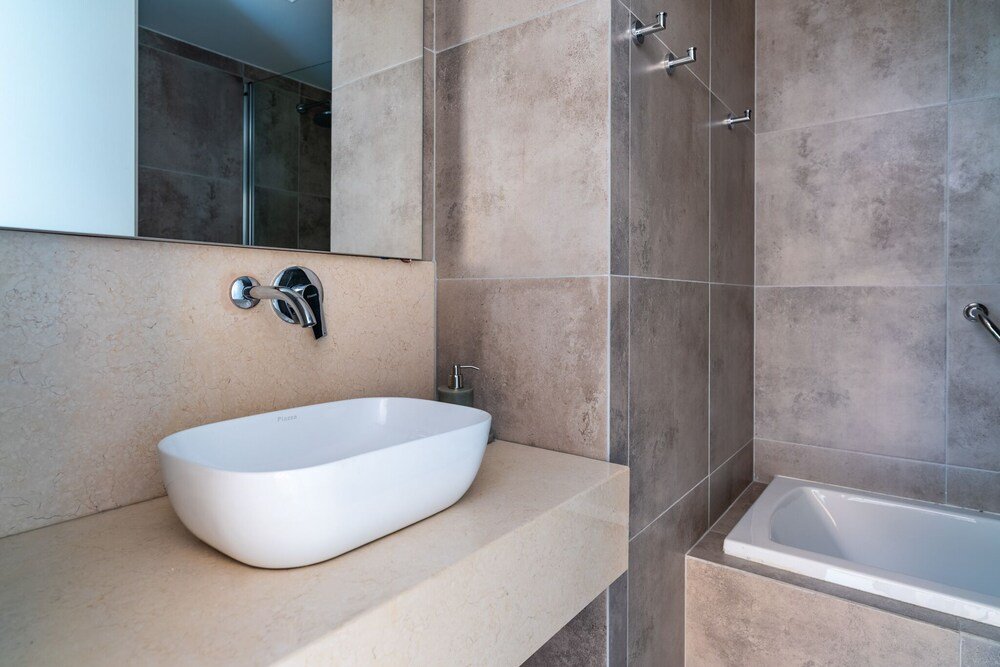 Baño moderno con un gran lavabo blanco, espejo y bañera