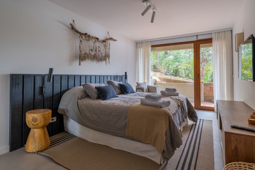 Dormitorio con cama, mesa de luz y vista al exterior