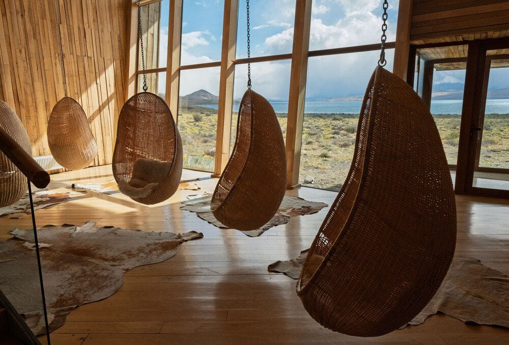 Room with large windows, hanging wicker chairs and wooden floor