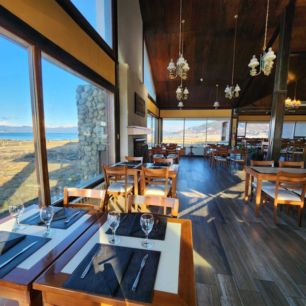 Restaurante con mesas y sillas de madera y grandes ventanales