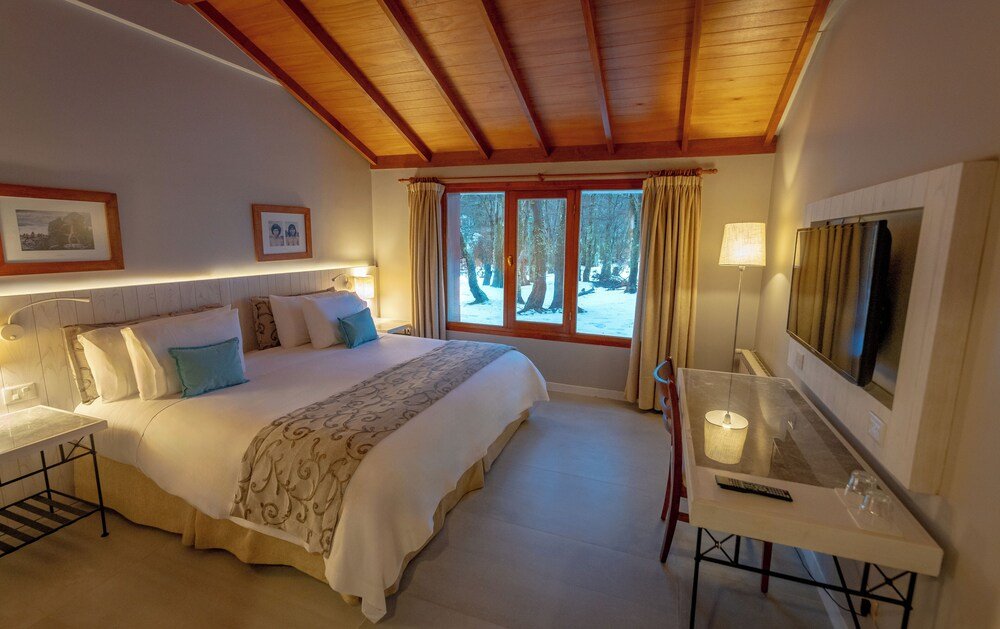 Habitación con cama grande, escritorio con TV y ventana