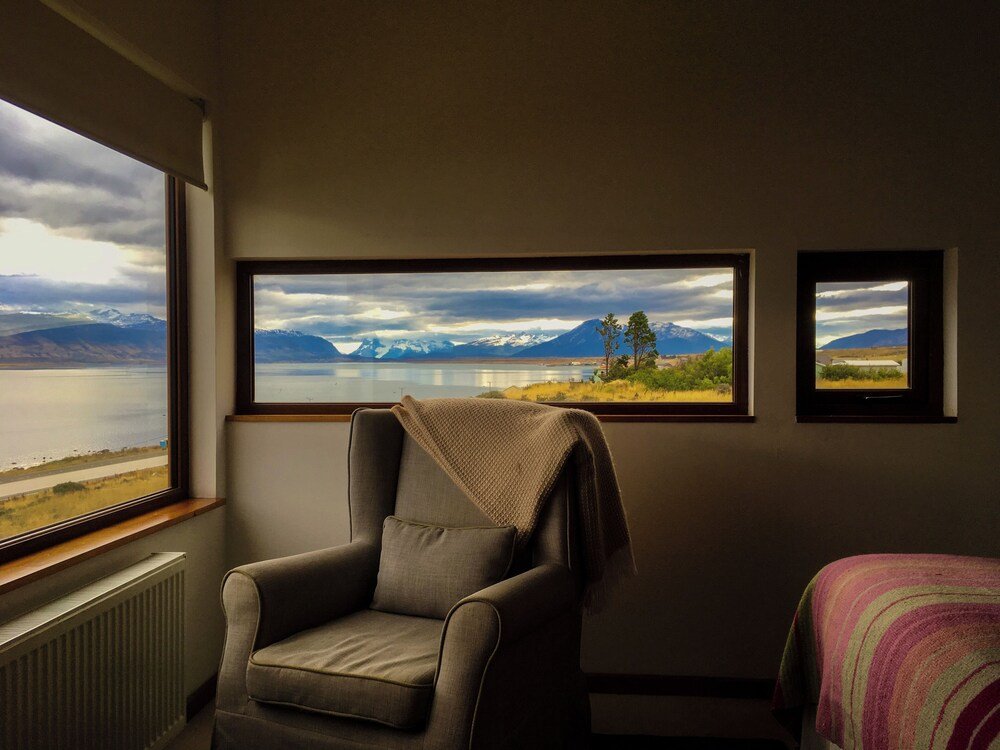 Room with a large window and a view of a lake and mountains