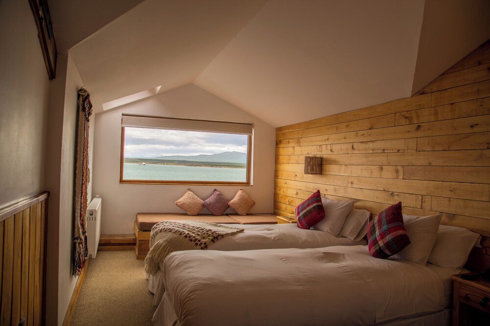 Bedroom with a large window, wooden walls and a bench