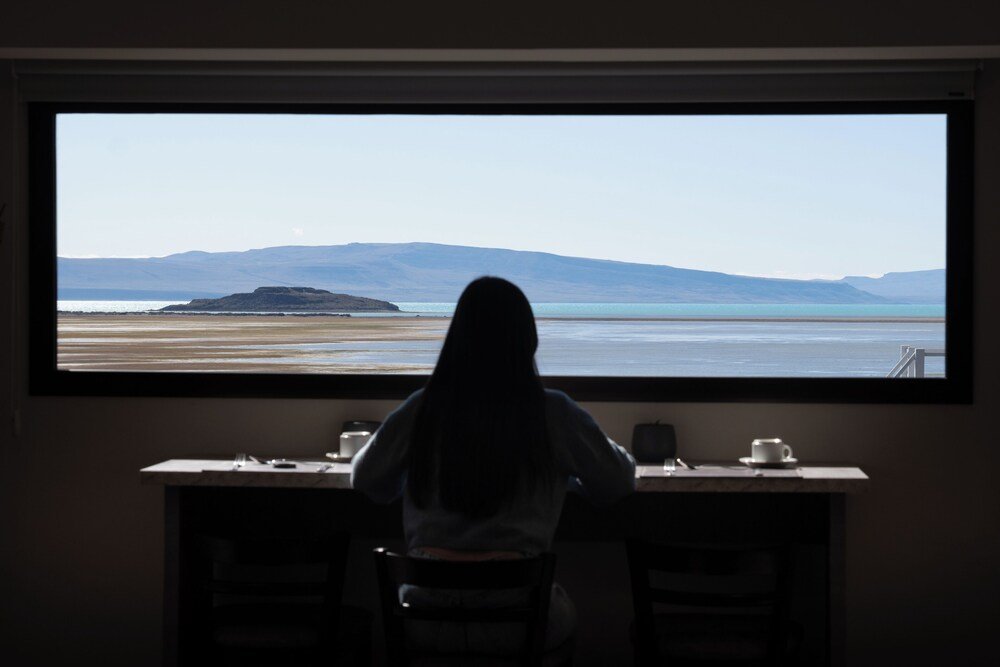 Escritorio con un gran ventanal sobre el lago y las montañas