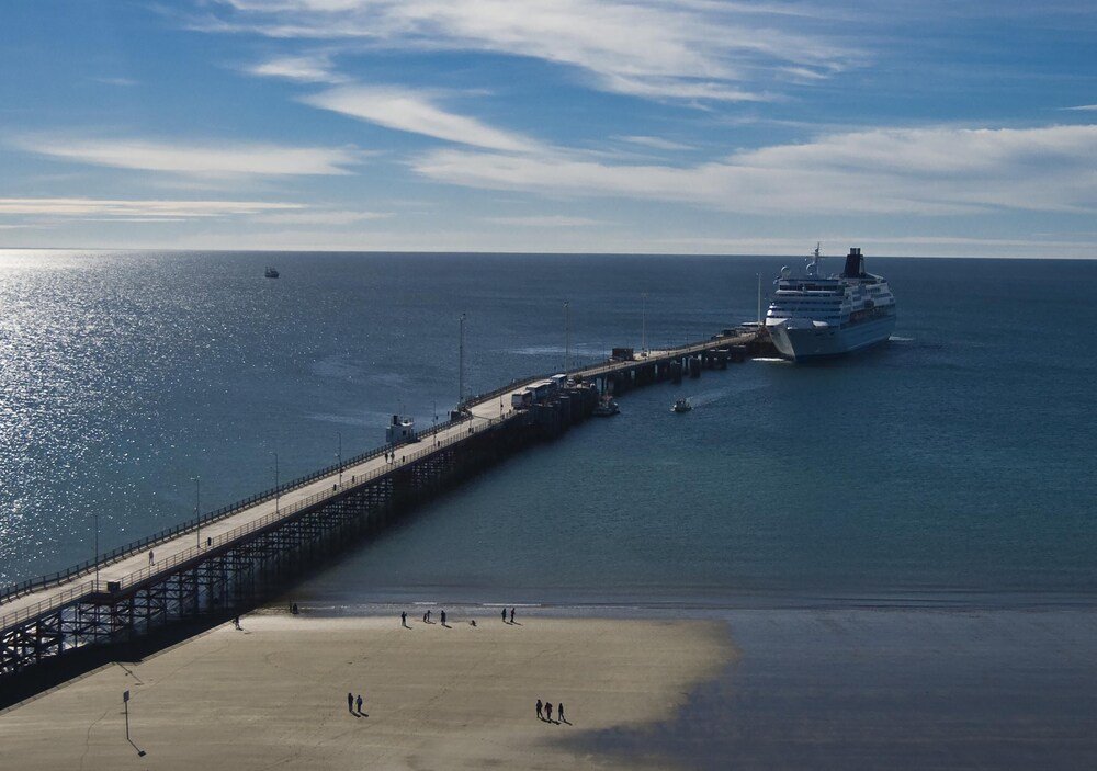 Pier extending into calm water with a cruise ship docked