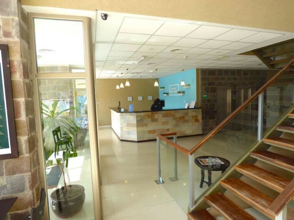 Hall del hotel con recepción, escalera y pared de vidrio